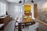 Sala de jantar com tons neutros e móveis de madeira e bar de madeira e parede amarela